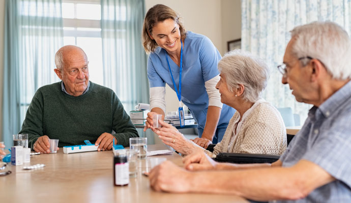 A caregiver distributing medication to elderly residents