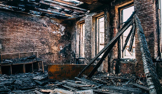 Interior of severely fire-damaged room with collapsed roof and debris
