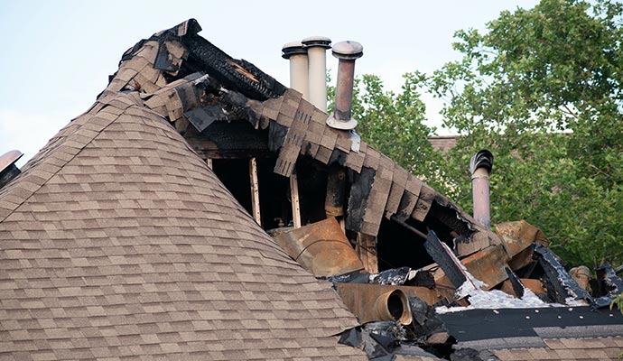 Fire-damaged roof with collapsed shingles and exposed wooden structure