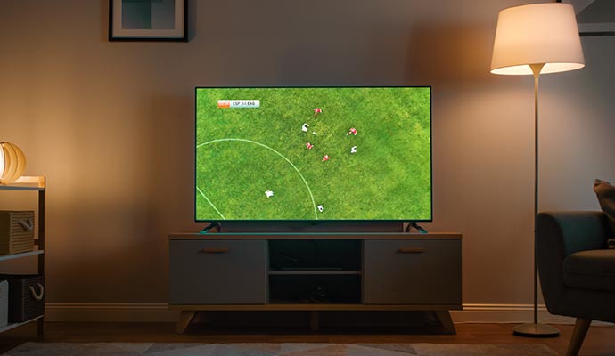 Tv showing a soccer match in a dimly lit living room