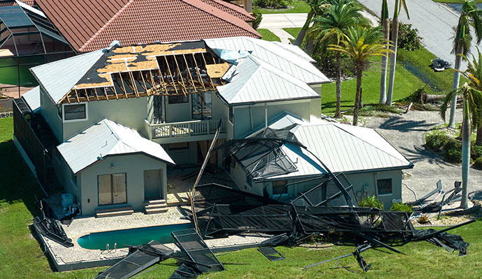 Residential house with destroyed roof and collapsed patio from tornado