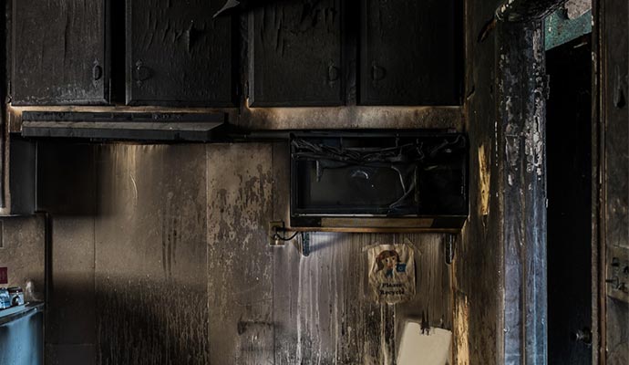 Kitchen area affected by smoke damage, showing soot-covered surfaces and appliances