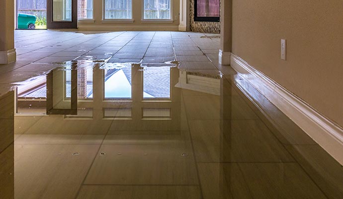 Interior floor with visible standing water on tiles due to water damage