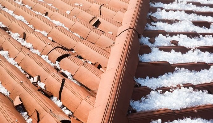 Roof with visible cracks and hailstones after severe hailstorm damage