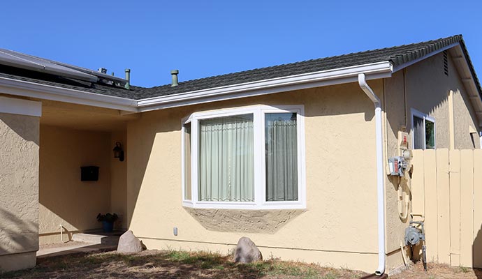 New gutters and downspouts installed along the exterior roofline of a residential home