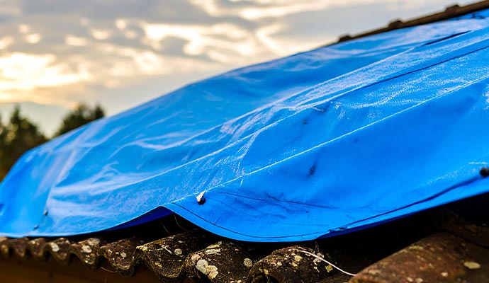 Blue tarp covering damaged roof to prevent further water intrusion after storm damage