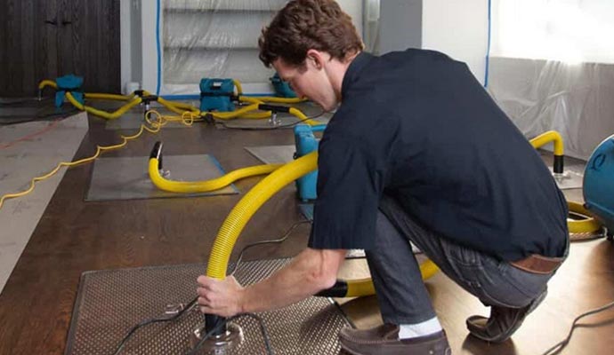 Technician installing up water damage restoration equipment Technician installing up water damage restoration equipment